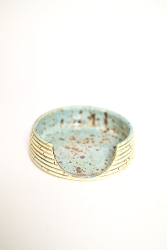 A handmade ceramic ring with a textured, ribbed gold-toned exterior and a speckled light blue-green glazed interior, shown on a plain white background.